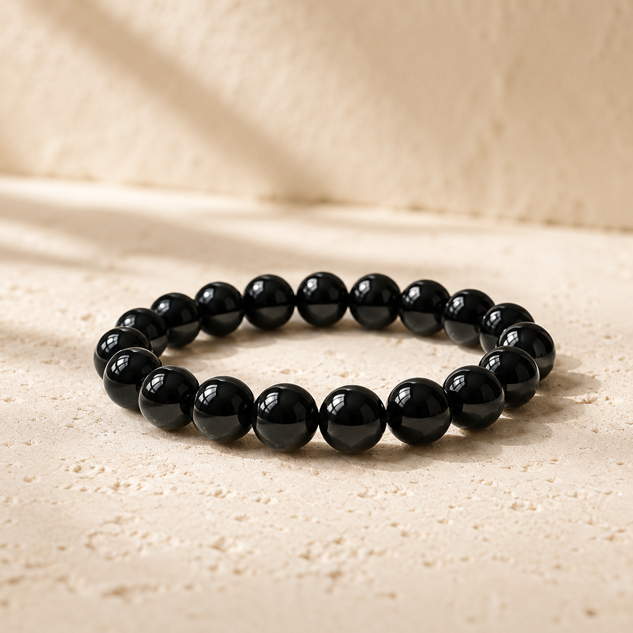 Natural black obsidian bead bracelet on warm ivory limestone