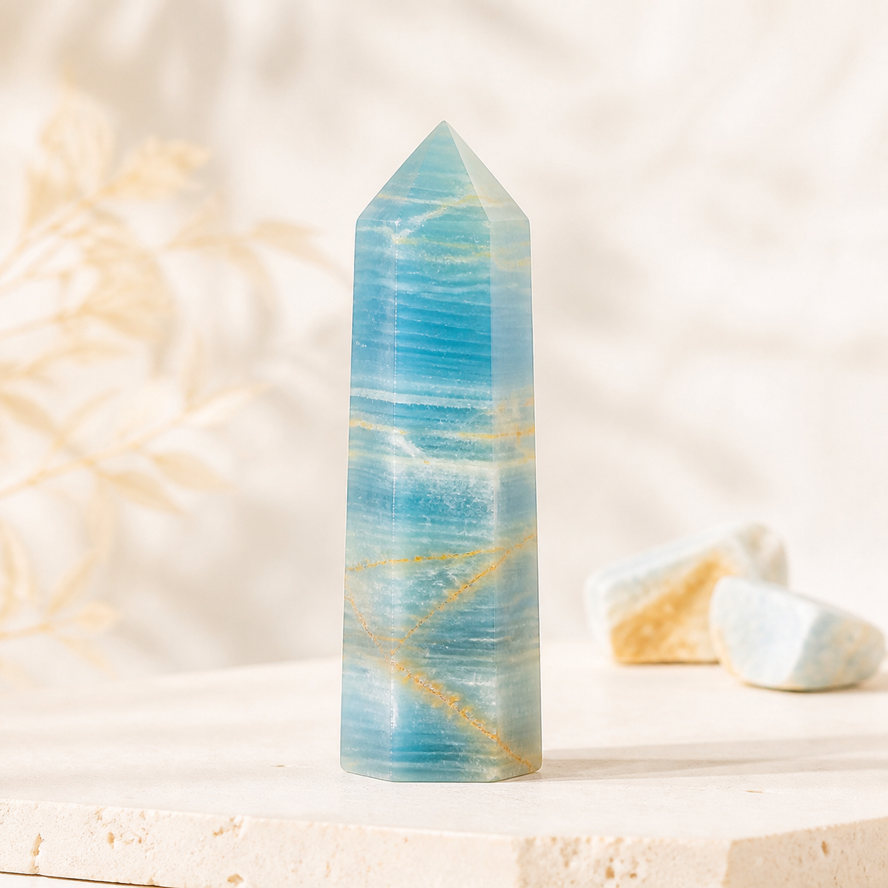 Aqua blue calcite crystal tower on warm ivory stone