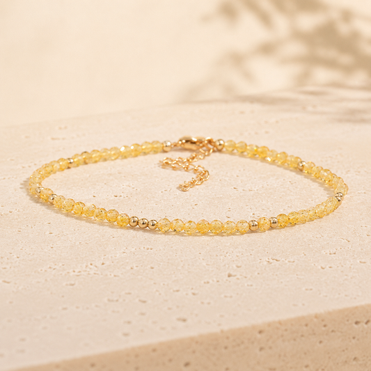 Minimalist golden natural stone bead bracelet on warm ivory limestone