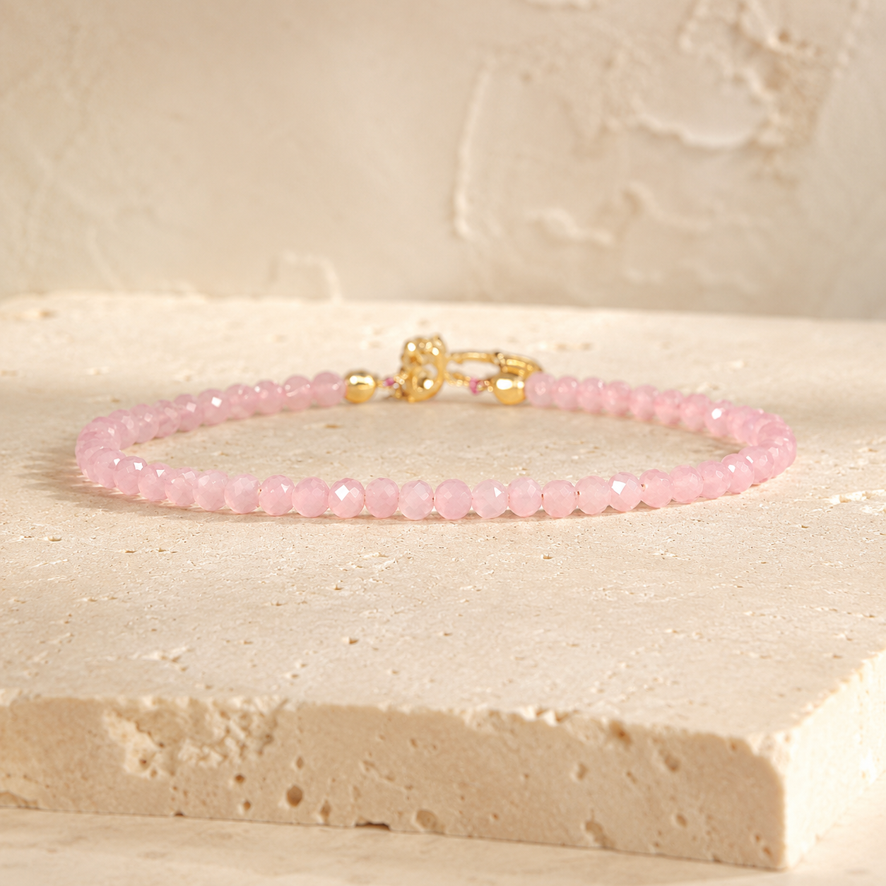 Minimalist blush rose quartz bead bracelet on warm ivory limestone
