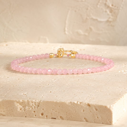 Minimalist blush rose quartz bead bracelet on warm ivory limestone