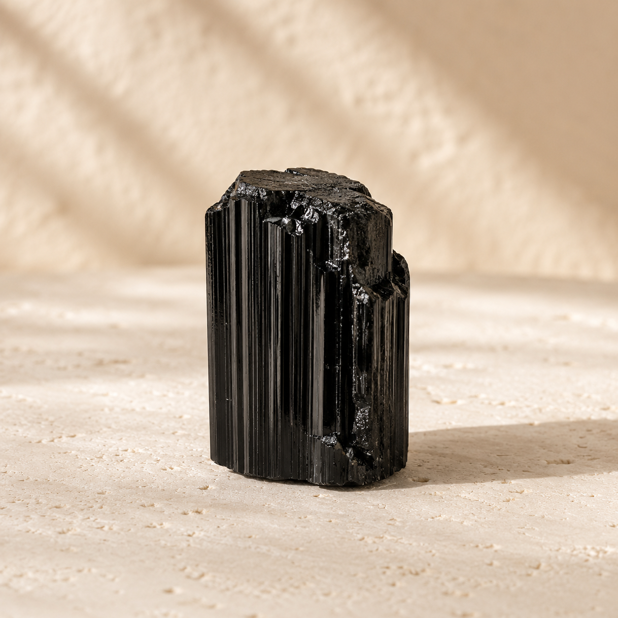 Natural black tourmaline raw stone on warm ivory limestone