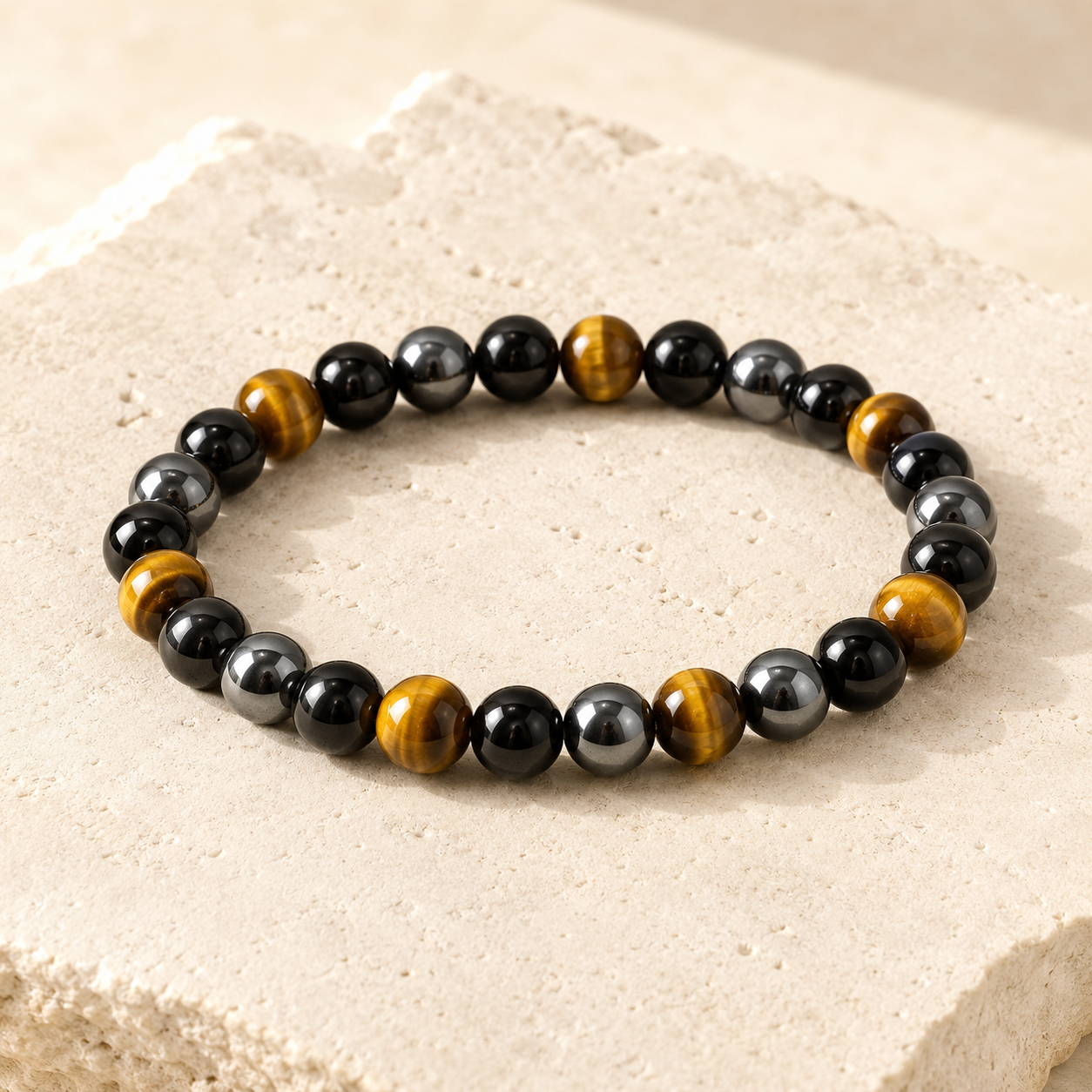 Obsidian hematite and tiger eye bead bracelet on warm ivory limestone